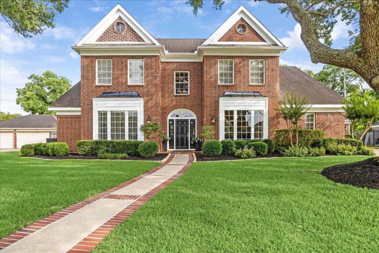 Luxurious two-story brick home with manicured lawn in Sugar Land, Texas, listed by top real estate brokers.