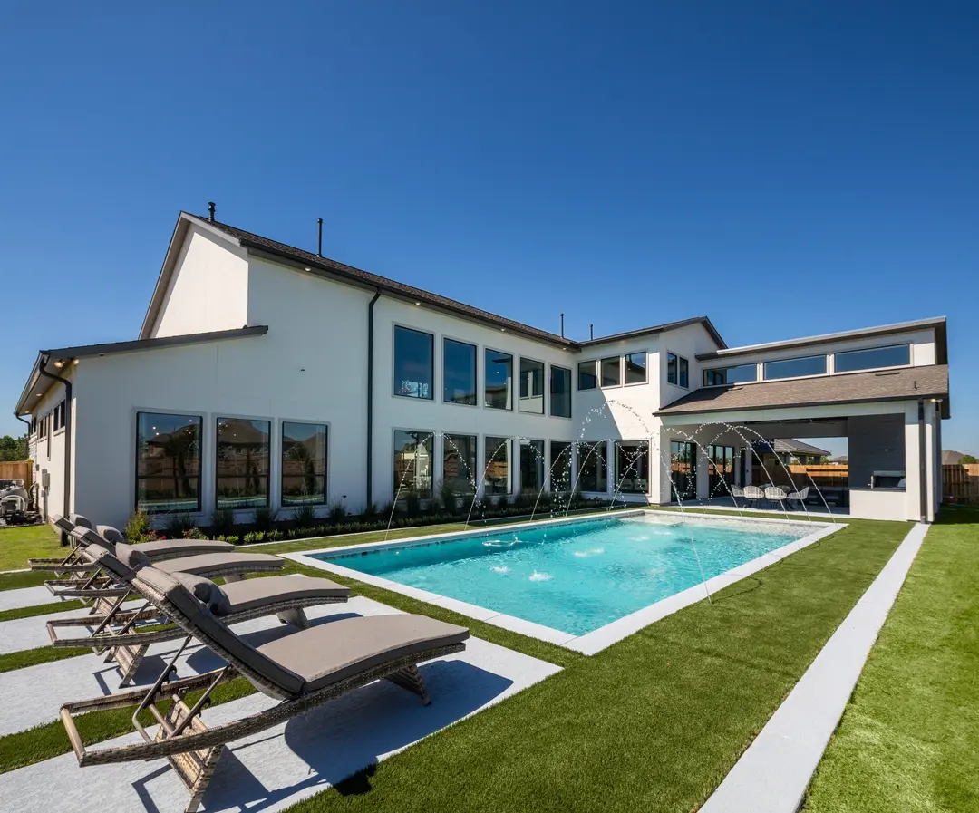 Luxurious backyard oasis with sparkling pool, lounge chairs, and water jets, part of premium properties offered by a dedicated house realtor in Sugar Land for ultimate relaxation.