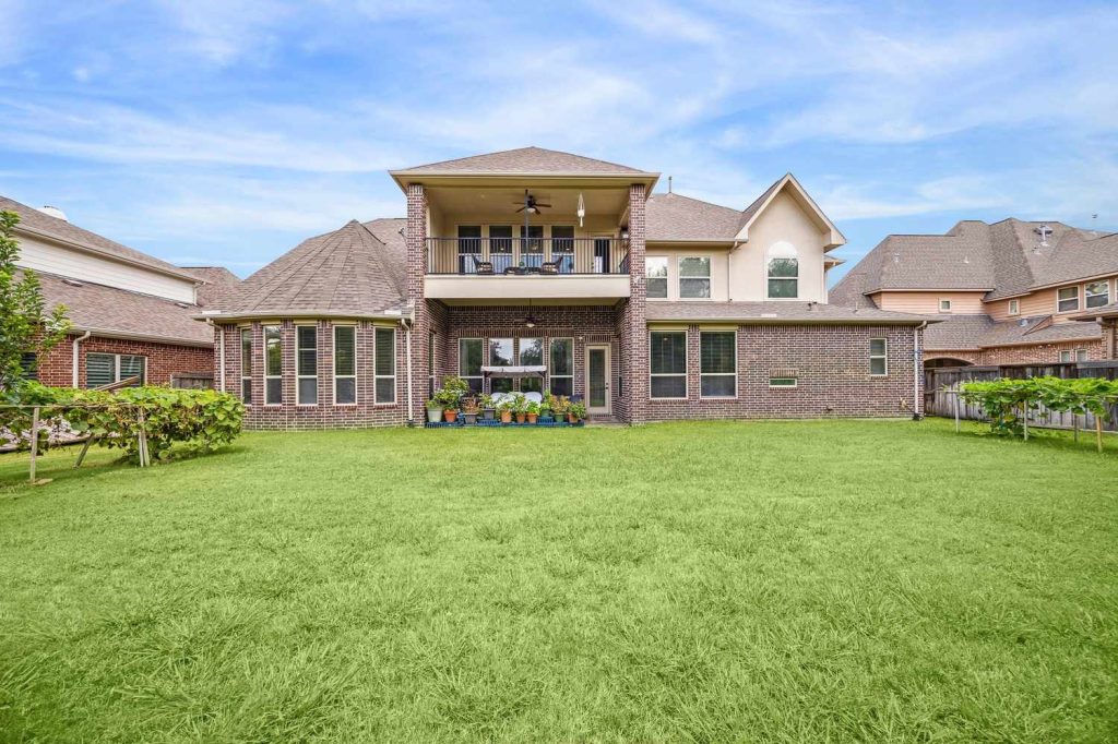 Charming brick home with stone accents, manicured lawn, and tree-lined walkway, offered by Real Estate Brokers Sugar Land.