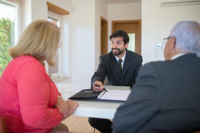A licensed real estate agent in Sugar Land discussing documents with clients at a meeting table.