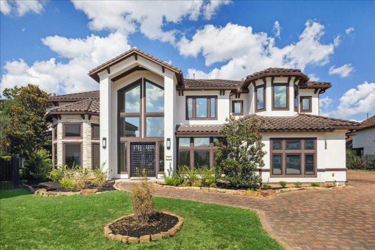 Elegant modern luxury home with large windows, white exterior, and tiled roof in Sugar Land, presented by expert real estate brokers.