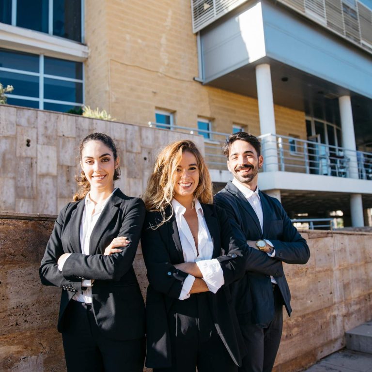 Three real estate agent brokers in Sugar Land standing confidently in front of a modern building.
