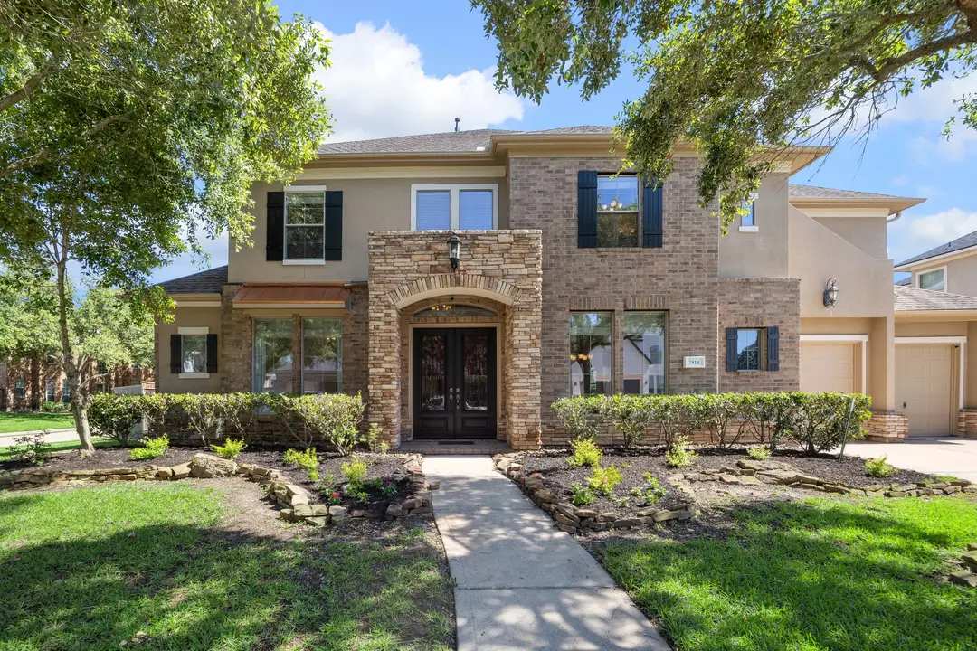 Grand Mediterranean-style mansion with lush green lawn and hedges, showcased by a licensed real estate broker in Sugar Land for luxury home buyers.