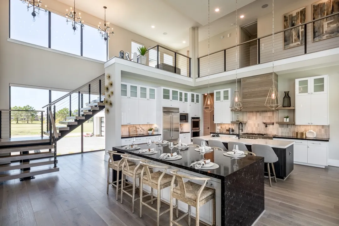 Spacious modern kitchen with island seating, staircase, and large windows, showcased by professional home selling agents in Sugar Land to attract buyers seeking elegant interiors.