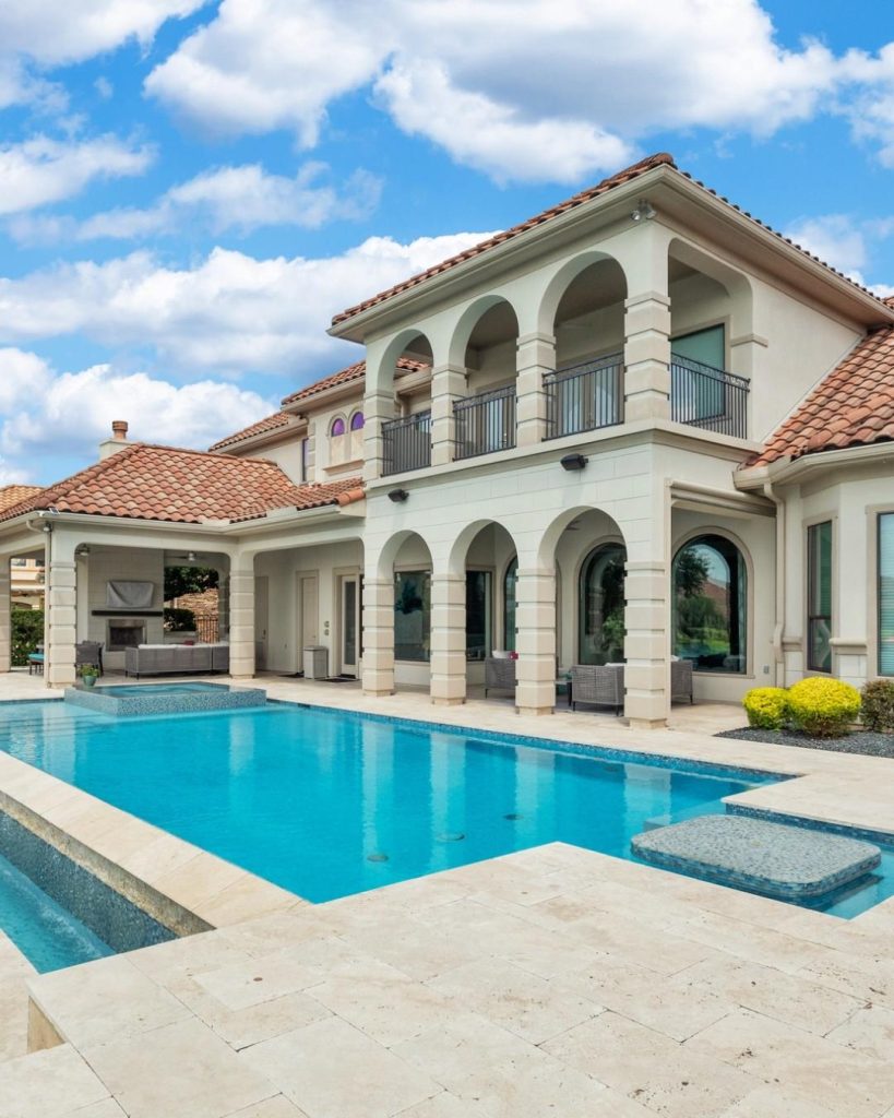 Elegant home with pool and arches under blue sky, featured by Realtor Broker Sugar Land.