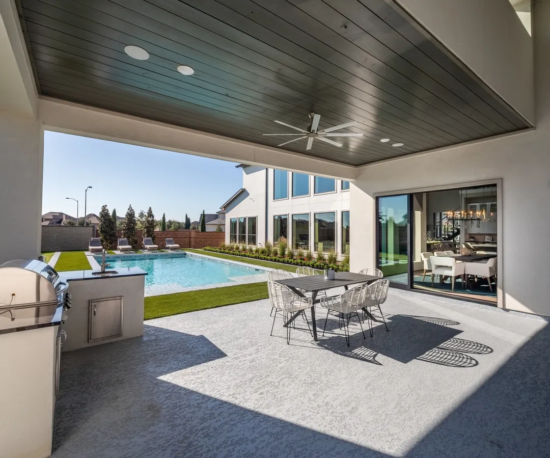 Luxurious covered patio with pool view, grill, and dining set, highlighting outdoor features marketed by skilled home selling agents in Sugar Land for premium property listings.