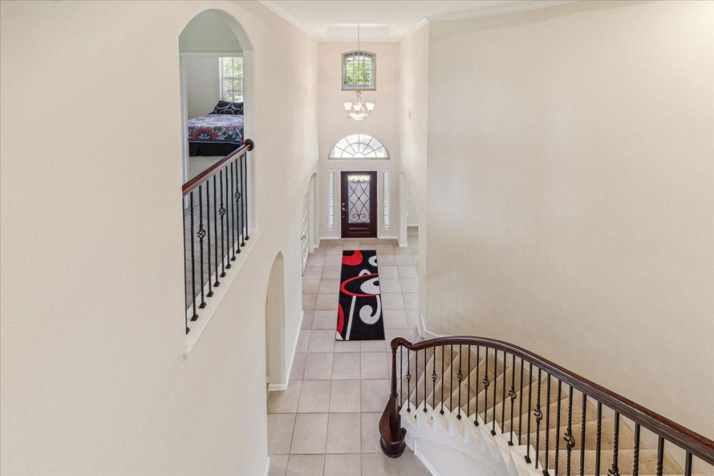 Spacious Sugar Land living room with fireplace and elegant staircase shown by expert home selling agents Sugar Land.