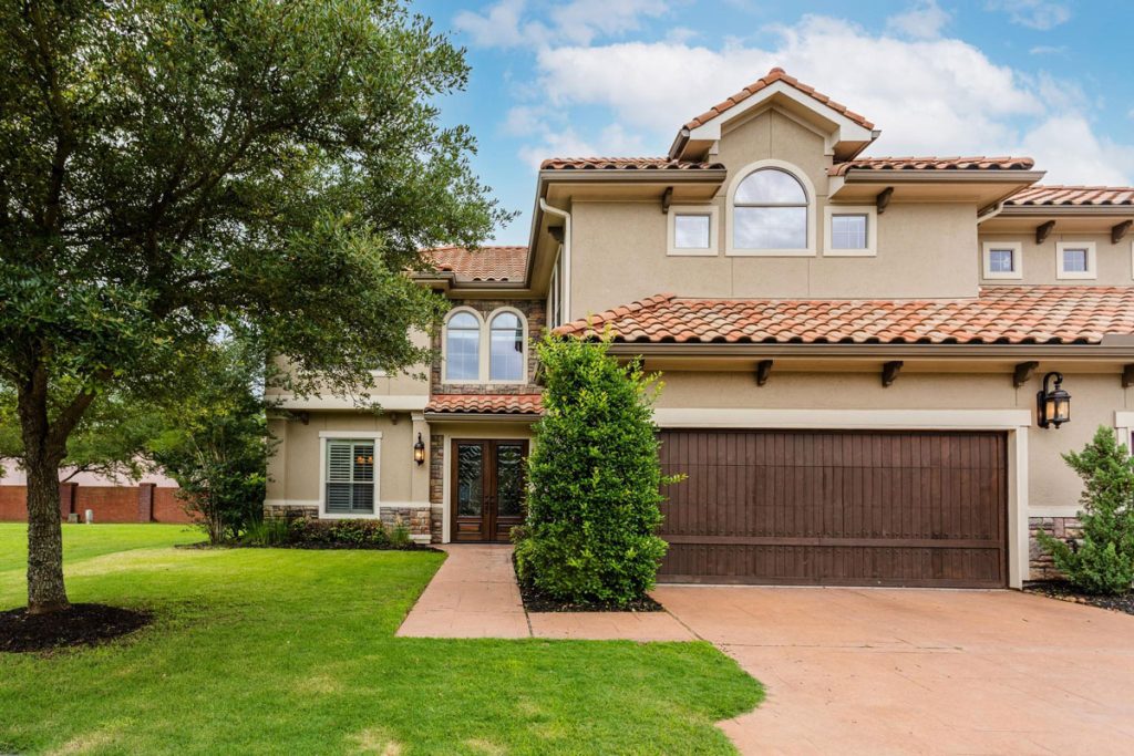 Elegant two-story home with stone accents and red-tiled roof listed by Estate Broker Sugar Land for upscale buyers.
