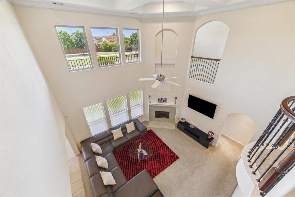 Grand Sugar Land entryway with chandelier and curved staircase featured by trusted home selling agents Sugar Land.