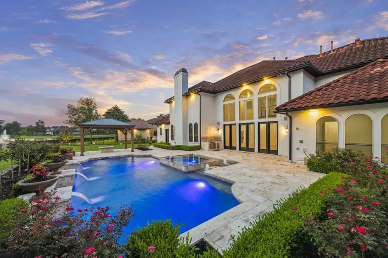Luxurious backyard with illuminated pool, spa, and pergola at sunset, presented by licensed real estate broker in Sugar Land.