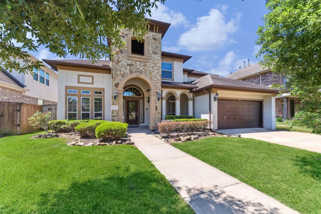 Luxury Sugar Land home with stone tower entry and landscaped yard listed by top home selling agents Sugar Land.