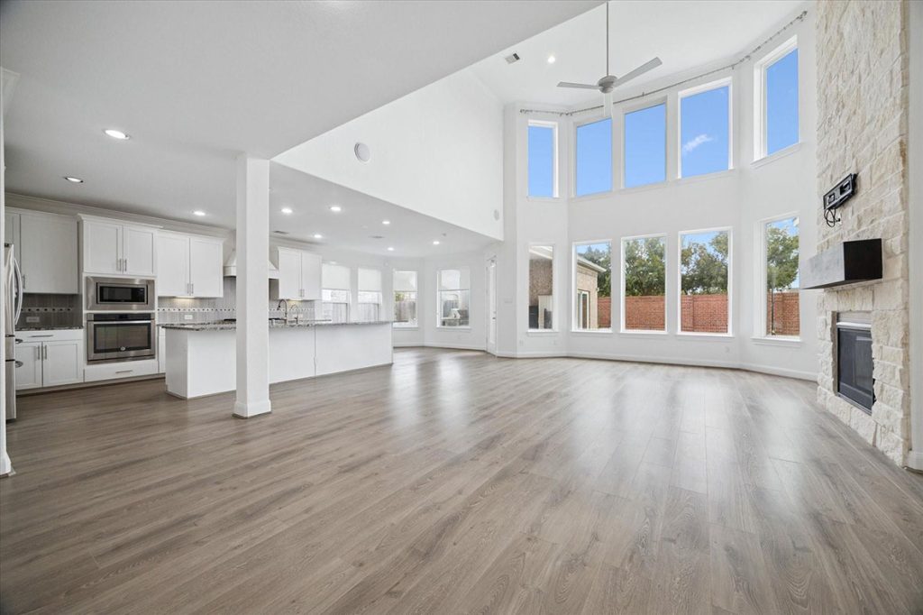 Open-concept kitchen and living with island, vaulted ceilings, and stone fireplace—estate broker sugar land showcasing bright interior