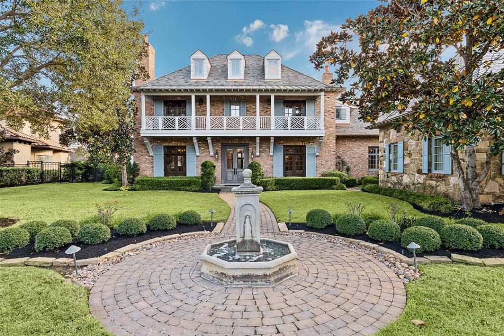 Elegant brick two-story Sugar Land home with dormers, balcony, manicured lawn and fountain, by house realtor sugar land