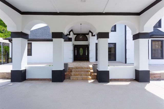 Elegant covered entryway with arched columns and grand double doors on a modern luxury home, represented by experienced Realtor in Sugar Land.