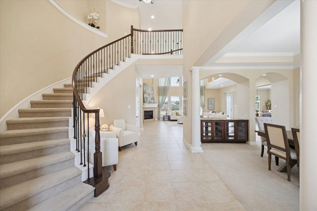 Elegant home interior with curved staircase, seating area, and open layout—ideal for asking about layout flow and design features during a home tour