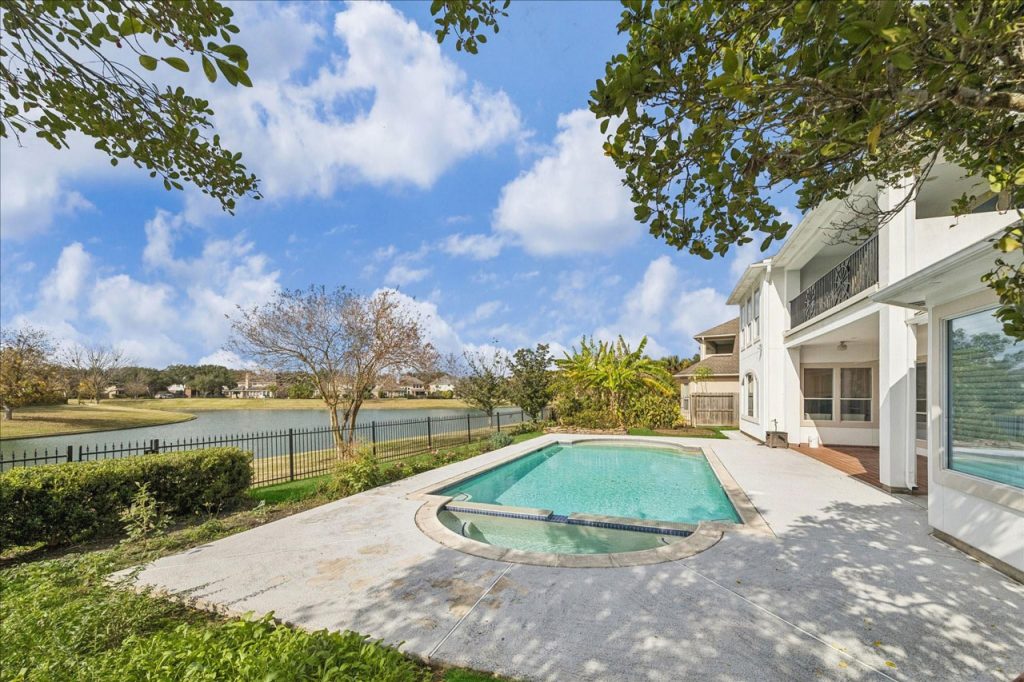 Luxurious backyard with sparkling pool, hot tub, and lake view in premium Sugar Land property represented by House Realtor Sugar Land.