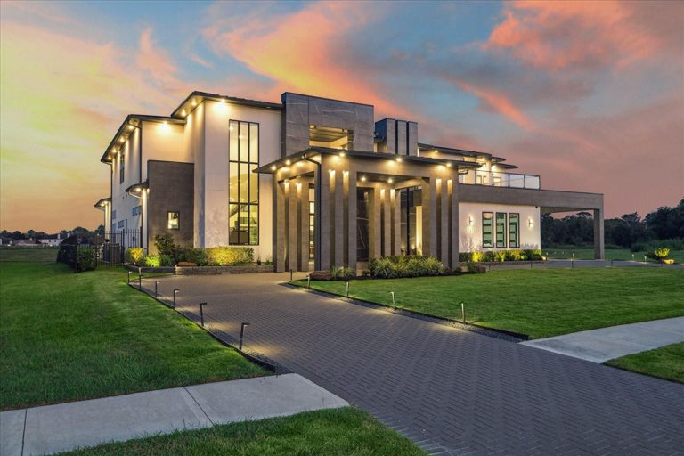 Modern Sugar Land two-story home at sunset with tall columns, large windows, and landscaped drive, by realtor broker sugar land