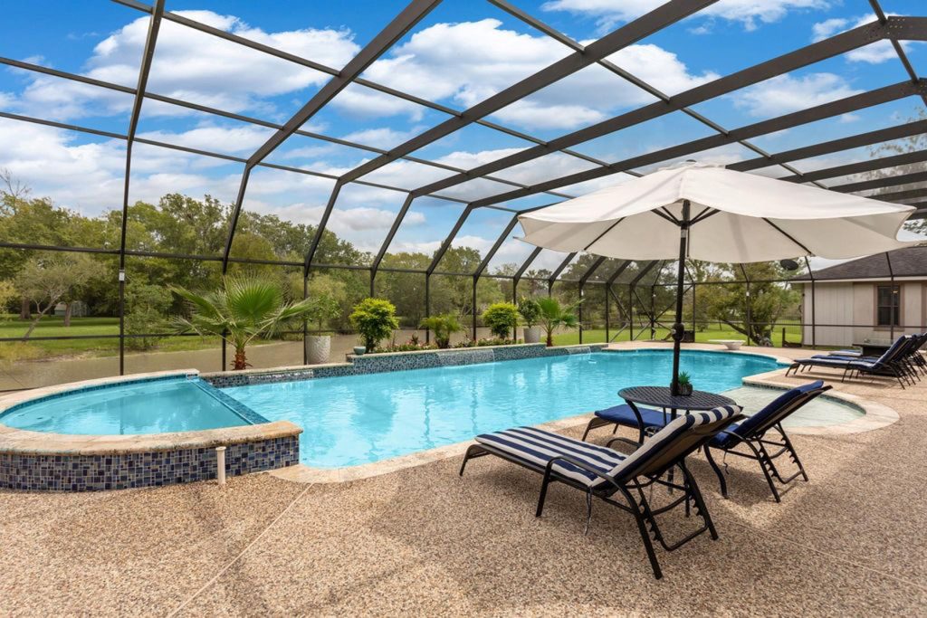 Screened in backyard pool with spa, loungers, and tropical landscaping featured by House Realtor Sugar Land for luxury listings.