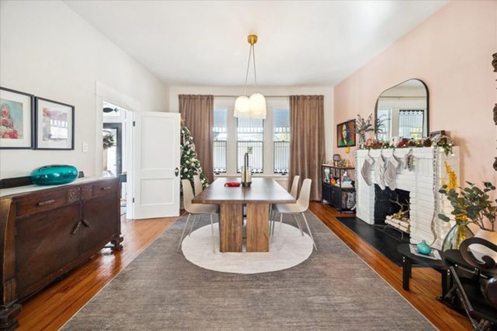 Spacious dining room with modern table, pendant lighting, fireplace, and holiday decor in elegant home listed by Home Selling Agents Sugar Land.