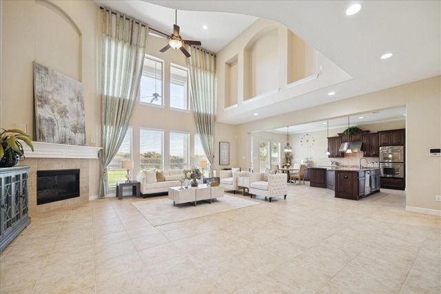 Spacious open-concept living room with high ceilings, elegant fireplace, and modern kitchen in luxury home, showcasing premium interiors at glass pipes Sapulpa.