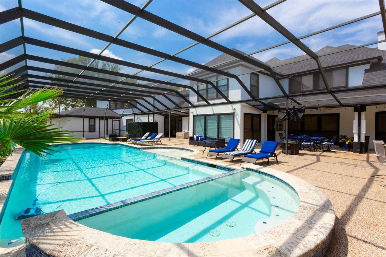 Stunning screened pool and spa with lounge chairs in backyard oasis of upscale home, marketed by premier Realtor in Sugar Land.