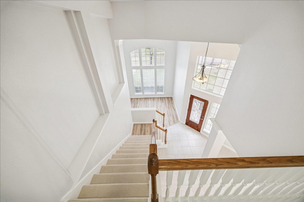 High-ceilinged entryway and staircase in a Sugar Land home, showing a bright foyer. A realtor can guide your home buying journey.