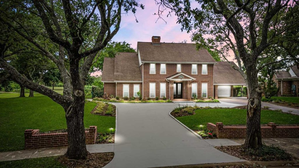 Licensed Real Estate Broker Sugar Land showcases luxury brick home with manicured lawn and sunset curb appeal.