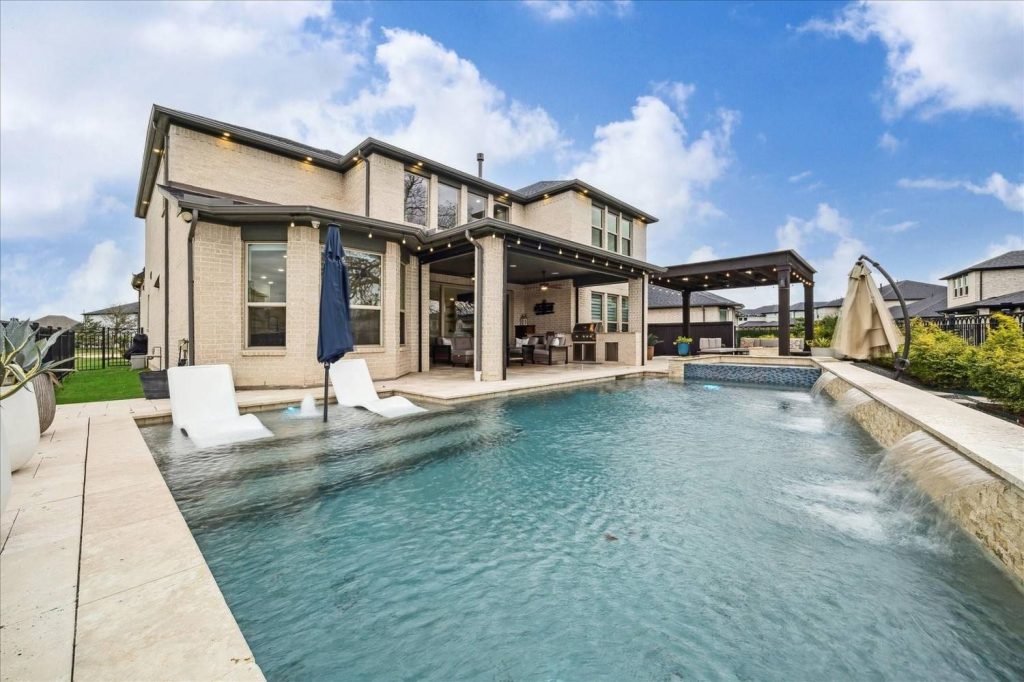 Stunning backyard retreat with sparkling pool, waterfall, covered patio, and outdoor seating – Licensed Real Estate Agent Sugar Land