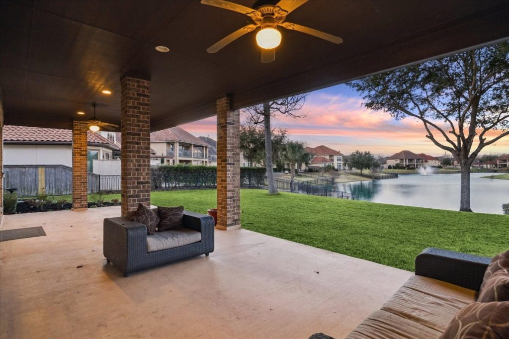 Covered outdoor patio with a serene sunset lake view, a key selling point from a licensed real estate broker Sugar Land.