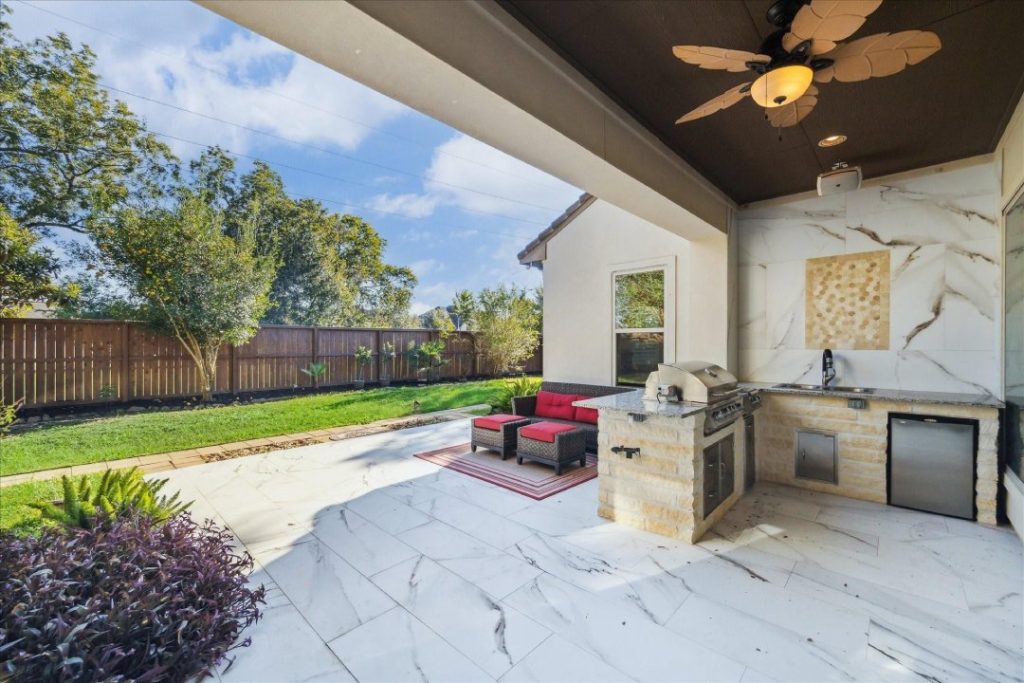 Cozy private courtyard patio with a tall stone fireplace, a unique feature presented by a local real estate agent broker Sugar Land.