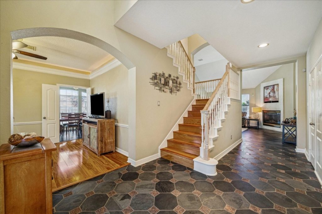 Foyer with slate floor and wood stairs, listed by a real estate agent broker Sugar Land.