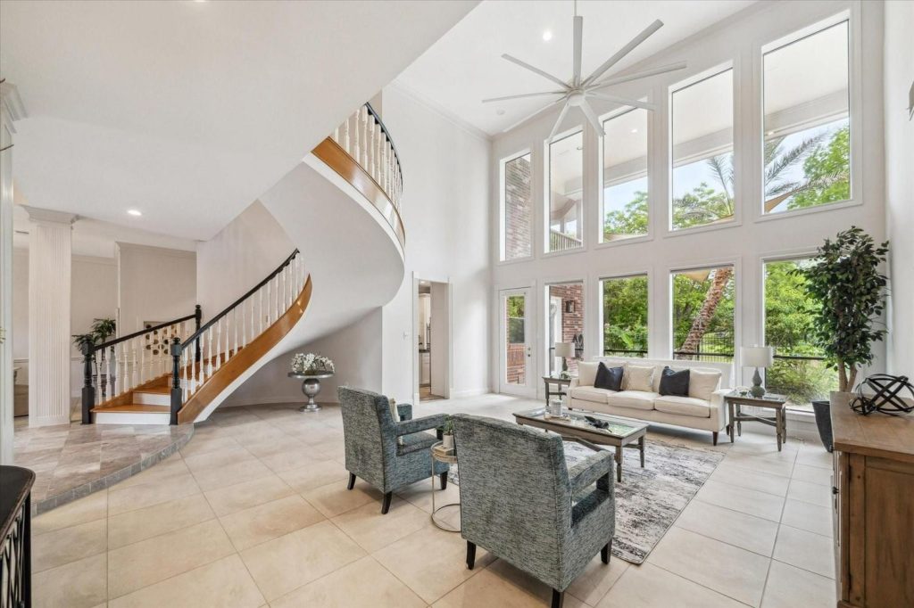 High ceilings and a curved staircase fill this bright living room from a top-tier home buying realtor Sugar Land.