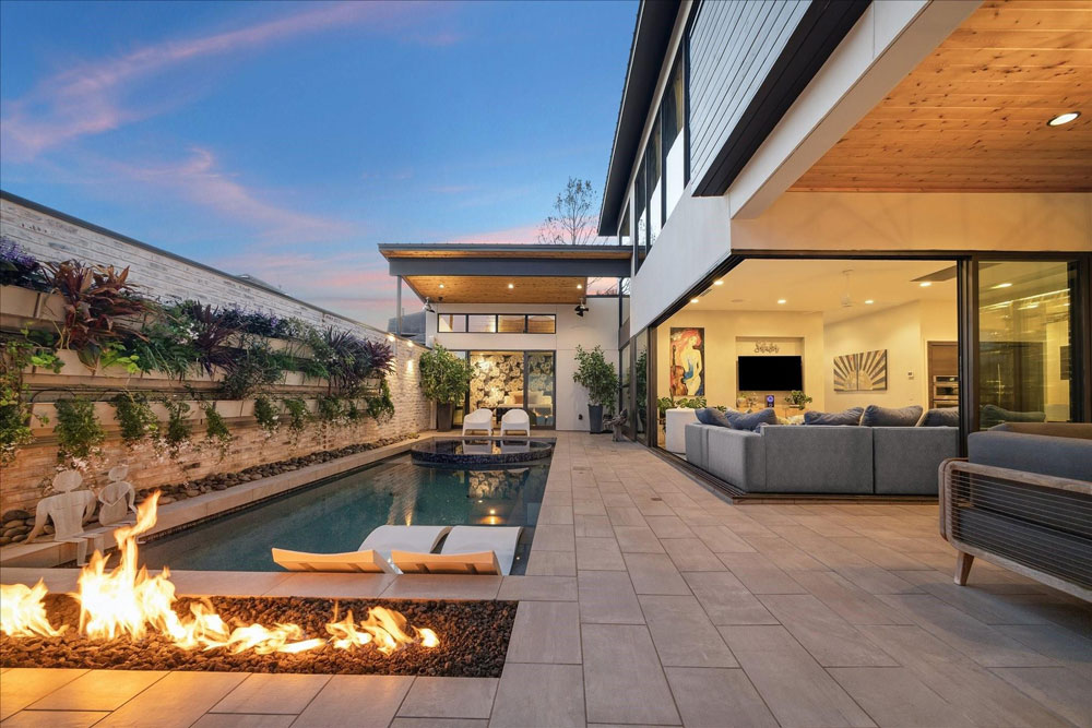 breathtaking modern backyard oasis with a linear fire feature and pool, showcased by a top Sugar Land luxury real estate agent.