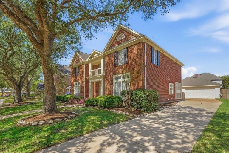 Traditional brick two-story home with a large oak tree and concrete driveway, listed by a top home selling realtor sugar land.
