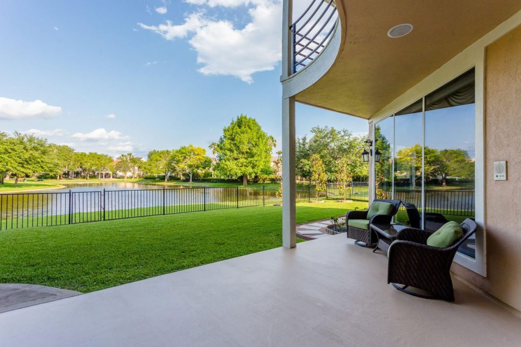 Covered patio overlooking a lake and fence in a Sugar Land home for sale by premier house selling agents Sugar Land.