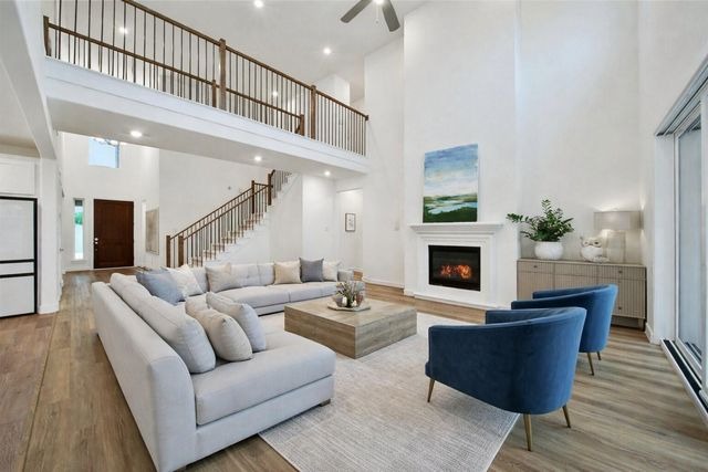 An open living room with vaulted ceilings, blue chairs, and a fireplace in a home from your House Selling Agents Sugar Land