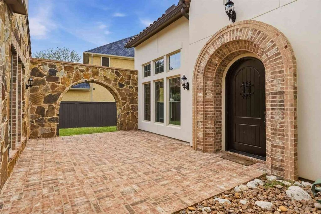 Inviting brick courtyard entrance of a Sugar Land home featuring stone arches, listed by your trusted House realtor Sugar Land.