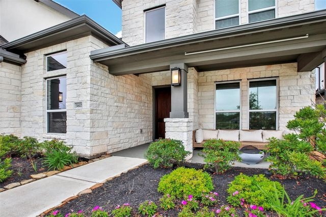 A charming modern farmhouse home entrance with white stone and a small patio, listed by your House Selling Agents Sugar Land.
