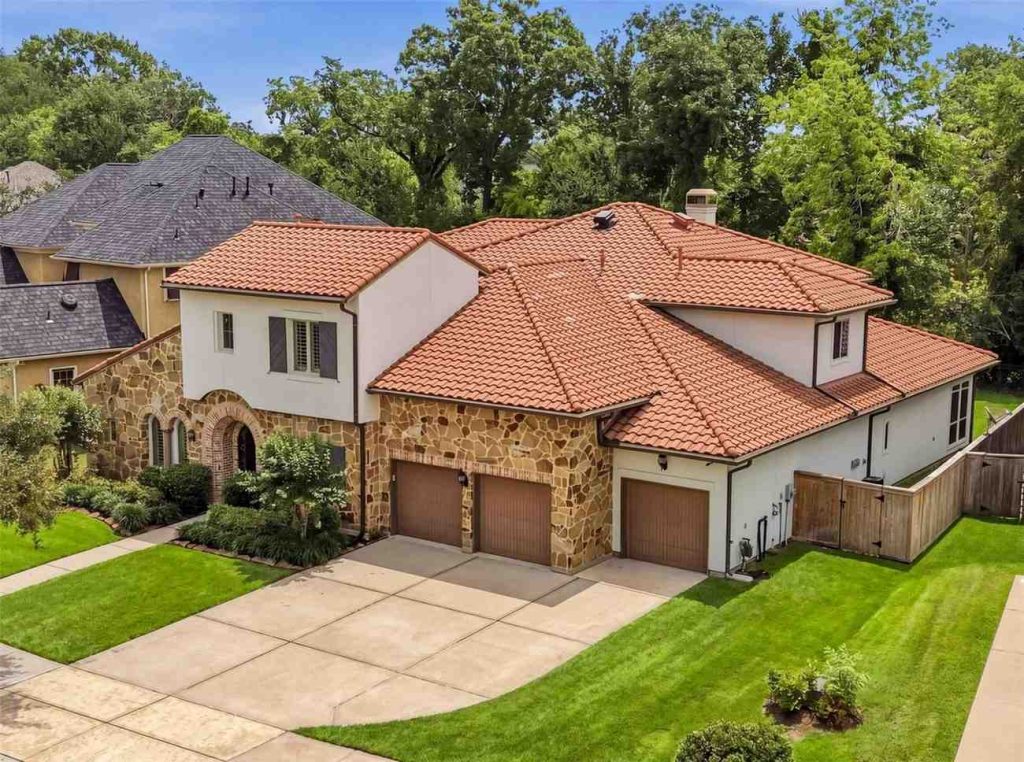Exterior front view of a Tuscan-style luxury home with stone facade and a three-car garage, available via Lease Properties Sugar Land.