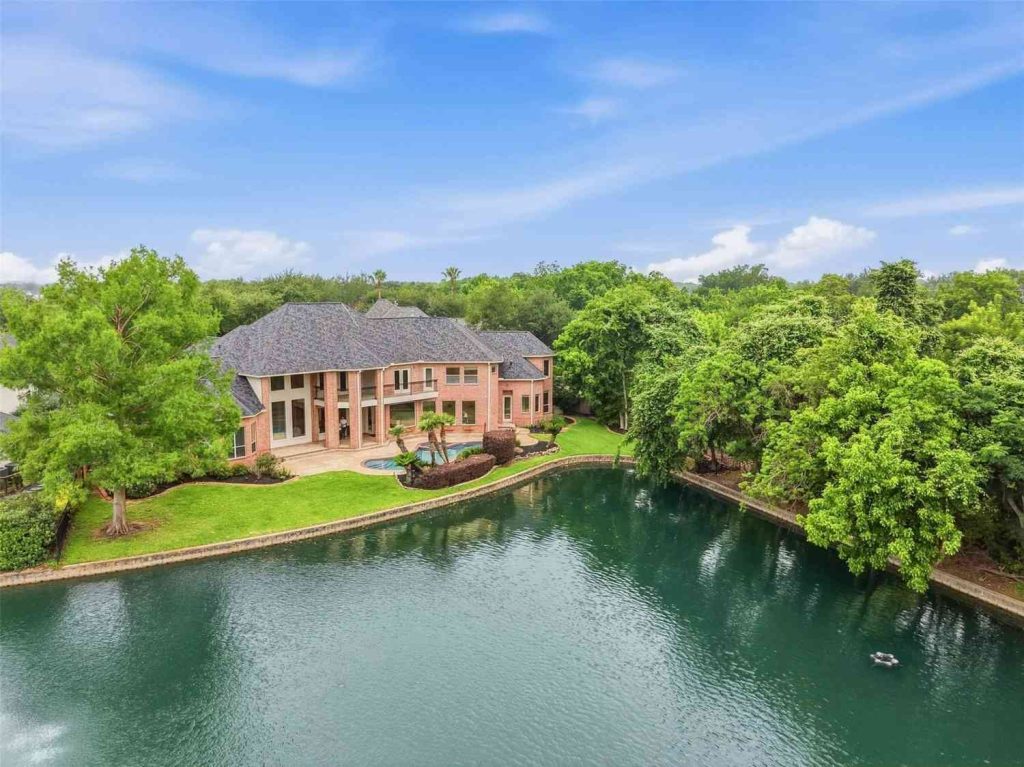 Picture your life at this luxury brick estate featuring a stunning pool and serene lake view, from your real estate agent Sugar Land