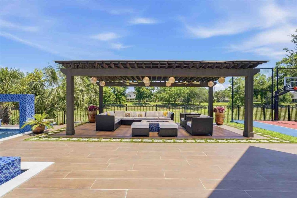 Ultimate outdoor entertainment under a massive custom pergola with comfortable sectional seating, shown by an estate broker sugar land