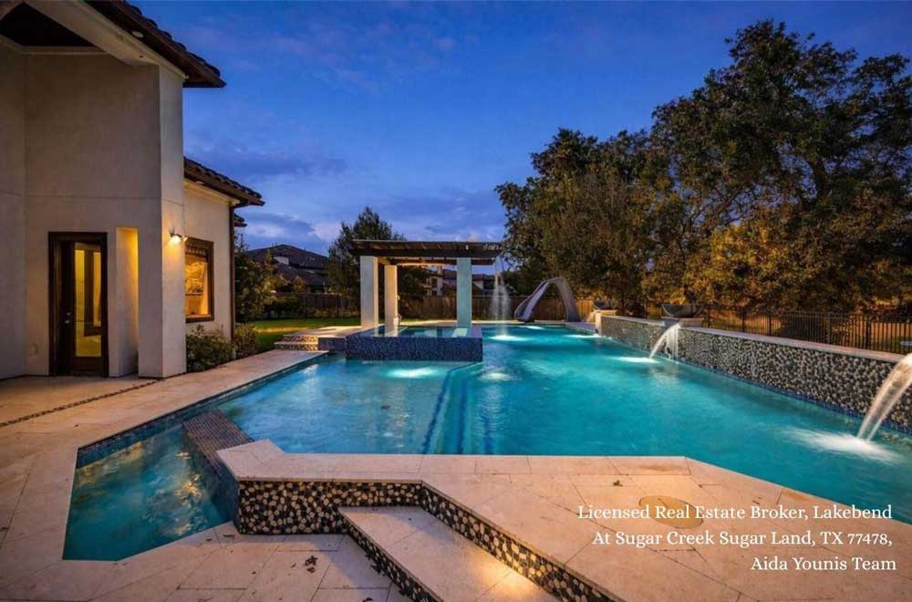 Luxury home backyard at Lakebend at Sugar Creek in Sugar Land Texas featuring a lighted custom swimming pool
