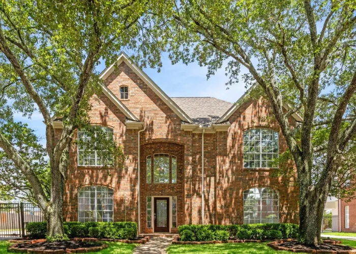 Beautiful two-story brick home exterior framed by large front yard trees at 2715 Oakland Drive, Sugar Land, TX 77479.