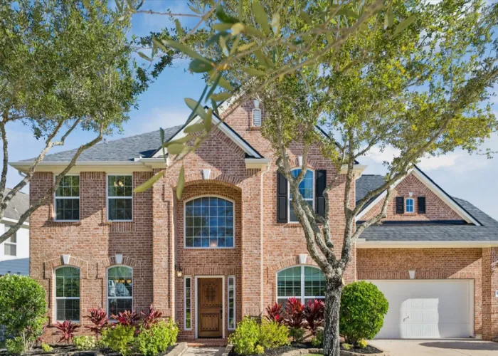 Stately red brick two-story home framed by front yard trees at 4303 Pensacola Oaks Lane, Sugar Land, TX 77479.