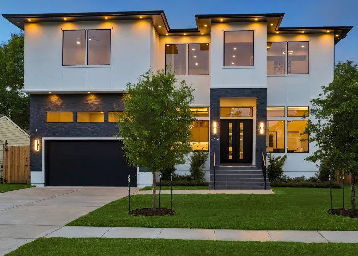 Modern luxury home exterior illuminated at twilight located at 4714 Tamarisk Street, Bellaire, TX 77401 with lush lawn.