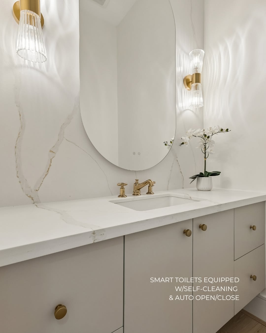Marble vanity and oval mirror inside a luxury new construction home Rice Museum District Houston bathroom.