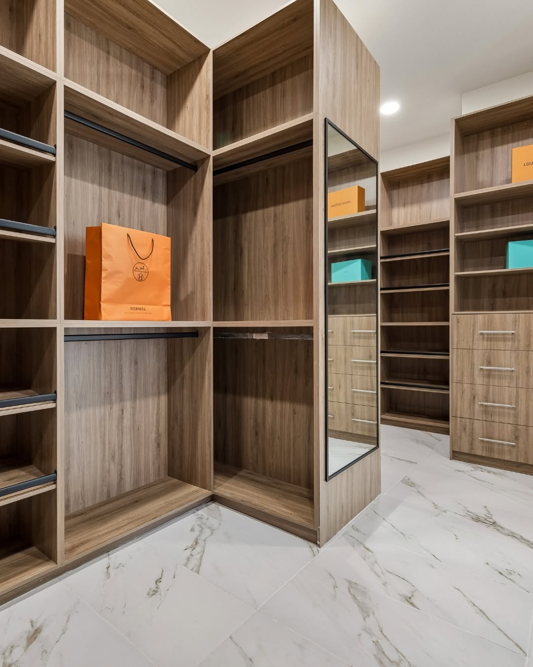 Custom walk-in closet with built-in wooden shelving in a new construction home Rice Museum District Houston.