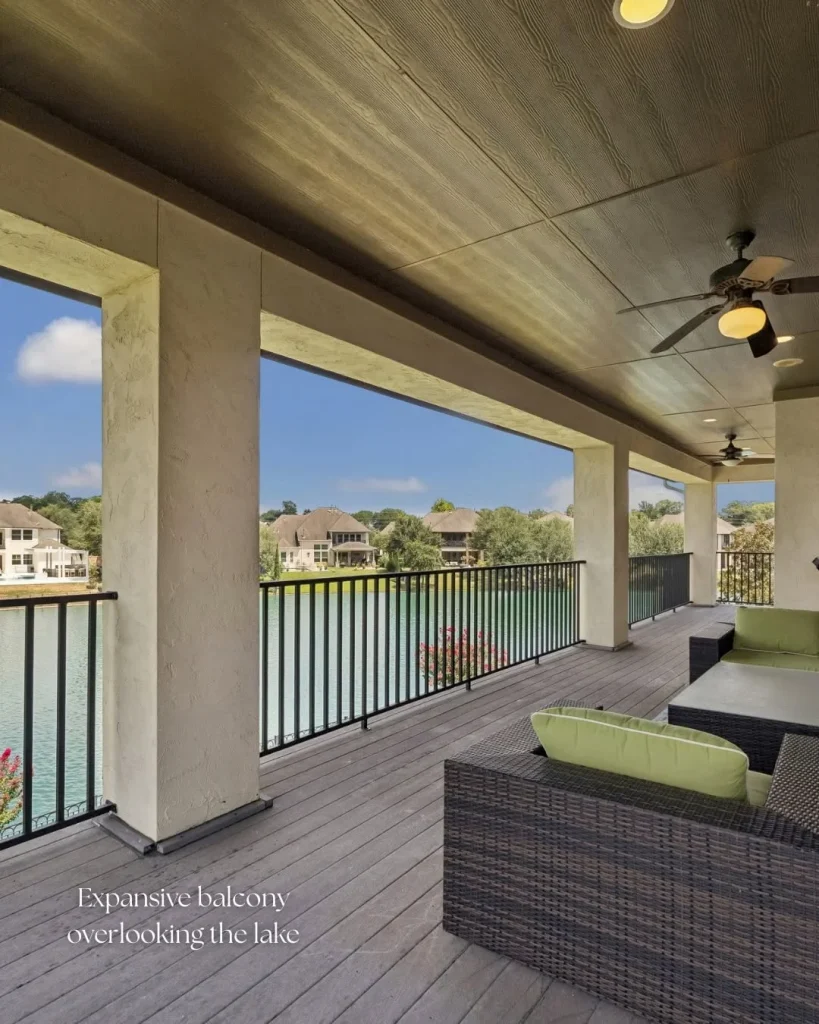 Expansive covered balcony with wicker seating overlooking scenic lake views at a Riverstone waterfront home for sale.